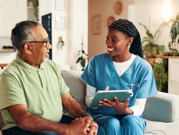 Caregiver talking with an older man on a sofa